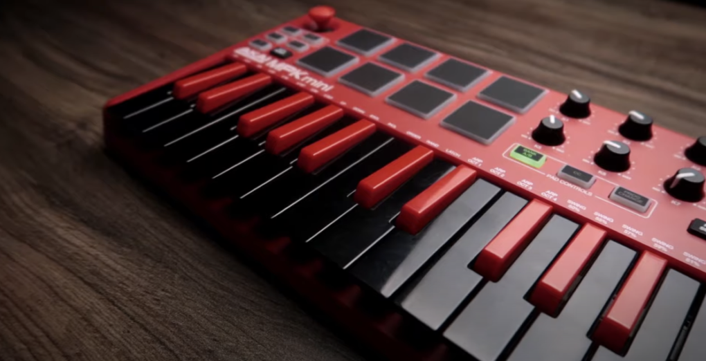 Photo of a black and red Akai Professional MPK Mini MKII MIDI controller placed on a wooden table