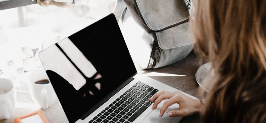 Girl sitting at a laptop and typing text.