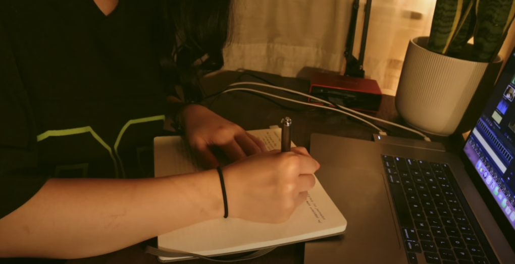 Photo of a hand holding a pen, poised to write something on a notebook