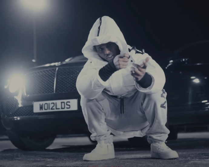 Photo of a guy wearing a hoodie, sitting in front of a car