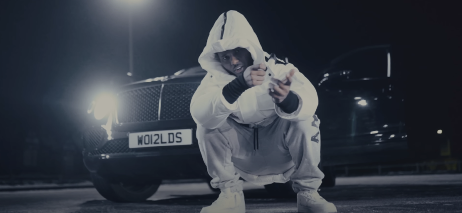 Photo of a guy wearing a hoodie, sitting in front of a car