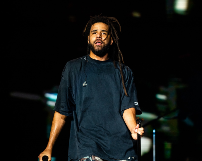 Cole, the renowned rapper, songwriter, and producer, performing on stage with passion and energy.