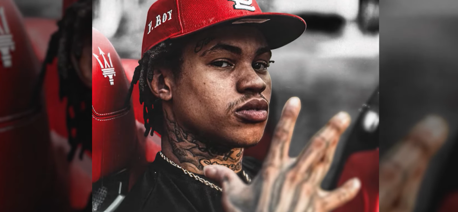 30 Deep Grimeyy in red hat looking at the camera with a raised hand up