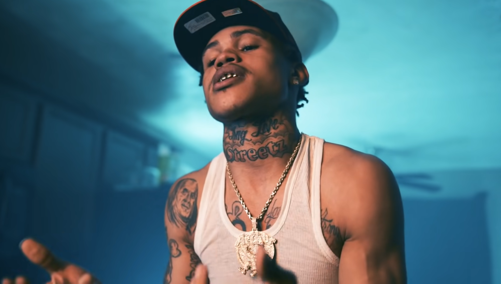 30 deep grimy in white t-shirt, hat, and silver chain in blue color room