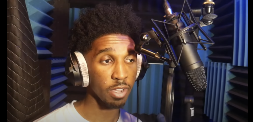 Photo of a guy singing into a microphone with a filter attached