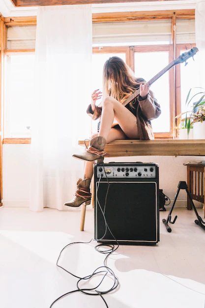 Girl playing the electric guitar sitting on the table