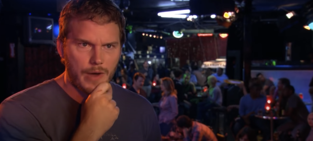 Photo of a man inside a bar, holding his head with both hands, appearing deep in thought