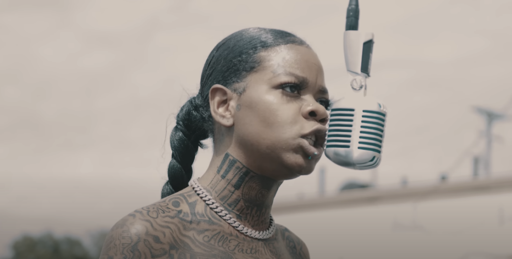Close-up shot of a tattooed woman singing into a microphone
