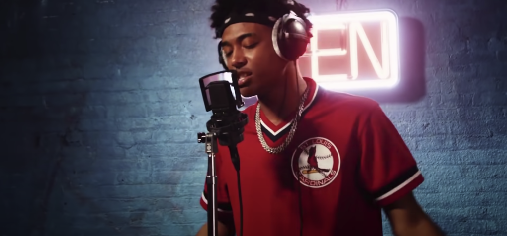 Photo of a guy singing into a recording microphone with a filter attached